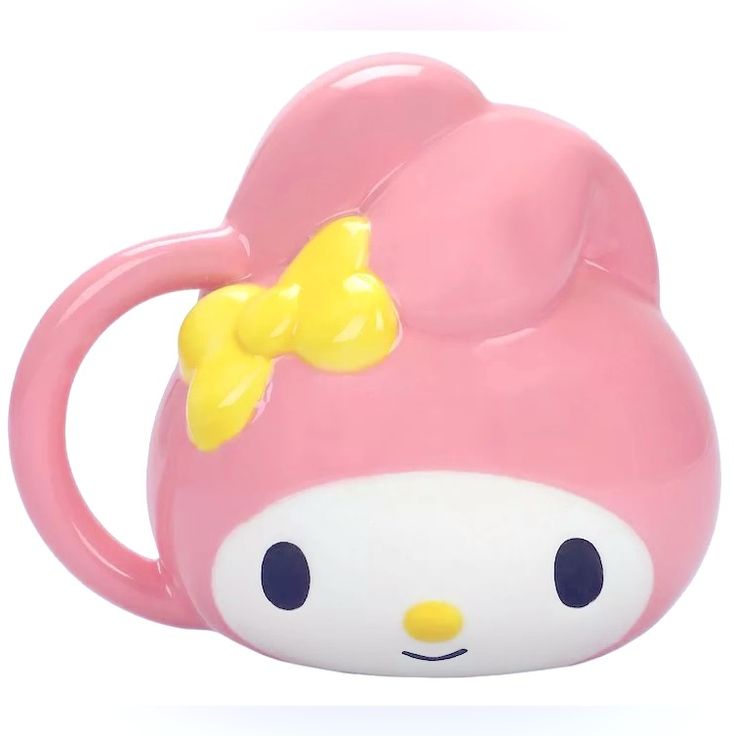 a pink hello kitty mug with a yellow bow on it's head and eyes