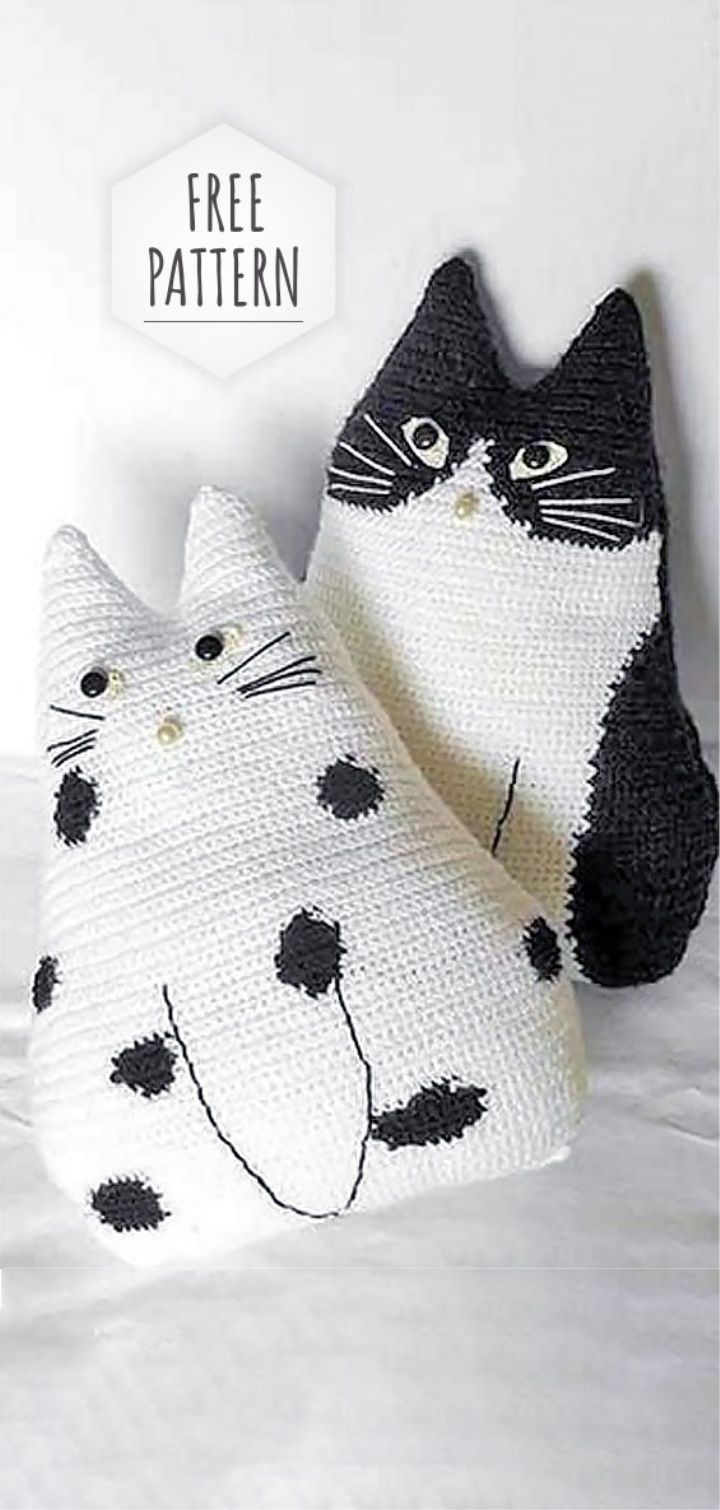 two crocheted cat pillows sitting on top of a white bed next to each other