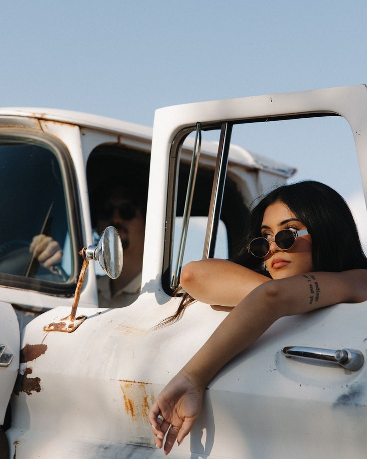 a woman sitting in the driver's seat of an old white truck