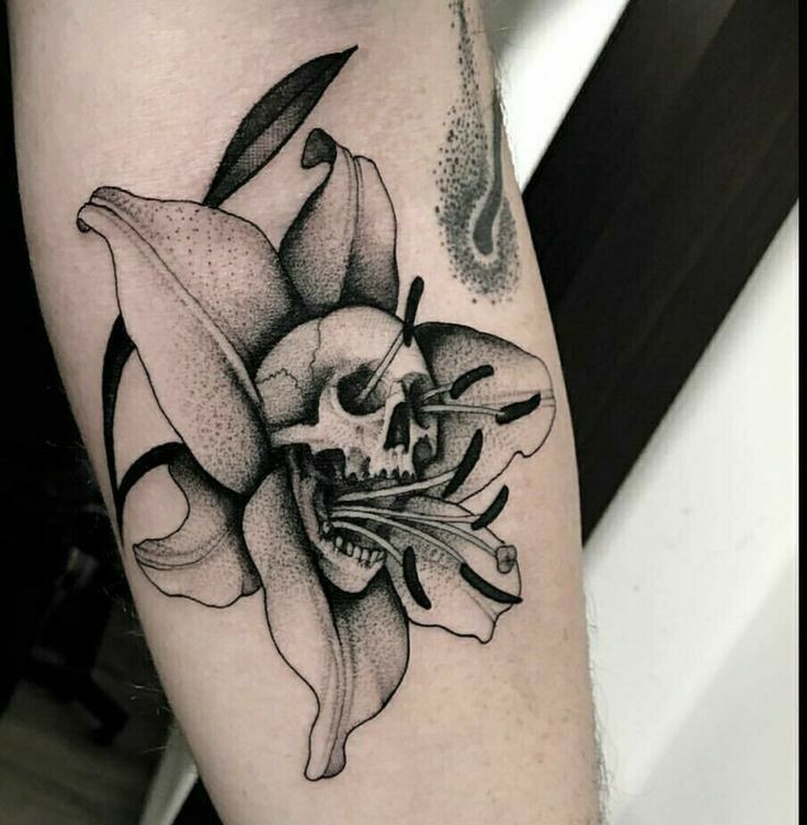 a skull and flower tattoo on the arm