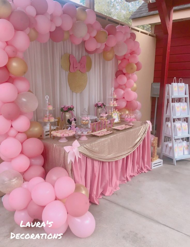 a pink and gold birthday party with balloons, streamers, cake and dessert table