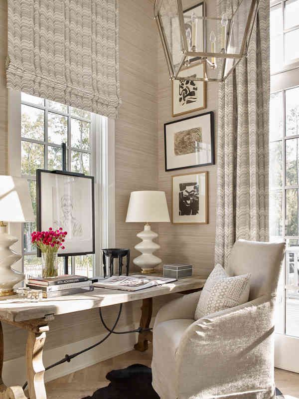 a white chair sitting in front of a window next to a desk with a lamp on it