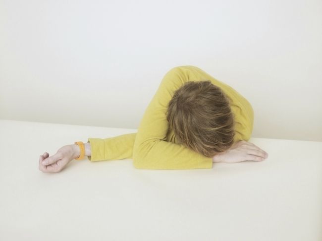 a person laying down on a bed with their head in their hands and arms behind their back