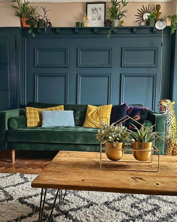 a living room filled with furniture and plants on top of a wooden table in front of a blue wall