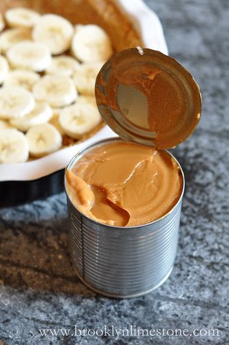 an open tin can filled with peanut butter next to a plate of sliced banana's