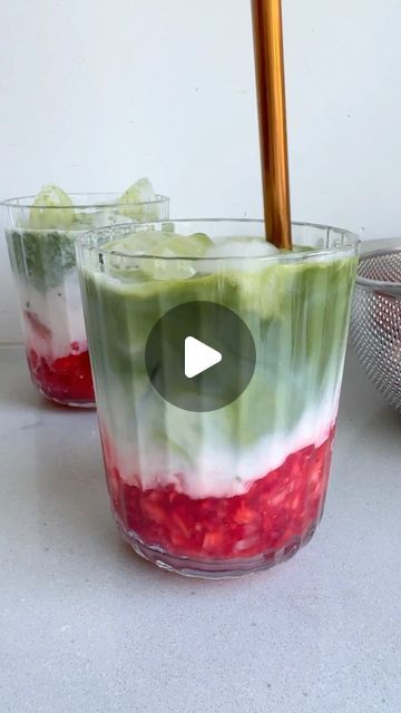 two glasses filled with food sitting on top of a white counter next to a strainer