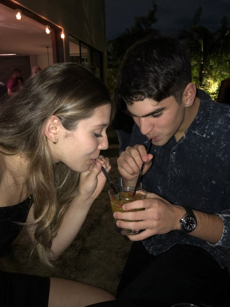 a young man and woman are sharing drinks