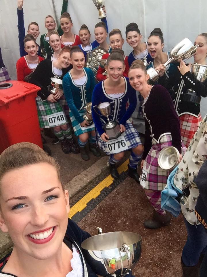 a group of young women standing next to each other in kilts and holding trophies