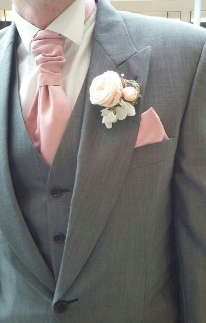 a man in a suit with a pink tie and flower boutonniere on his lapel