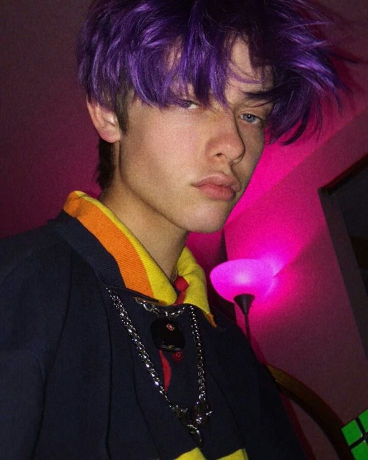 a young man with purple hair is looking at the camera