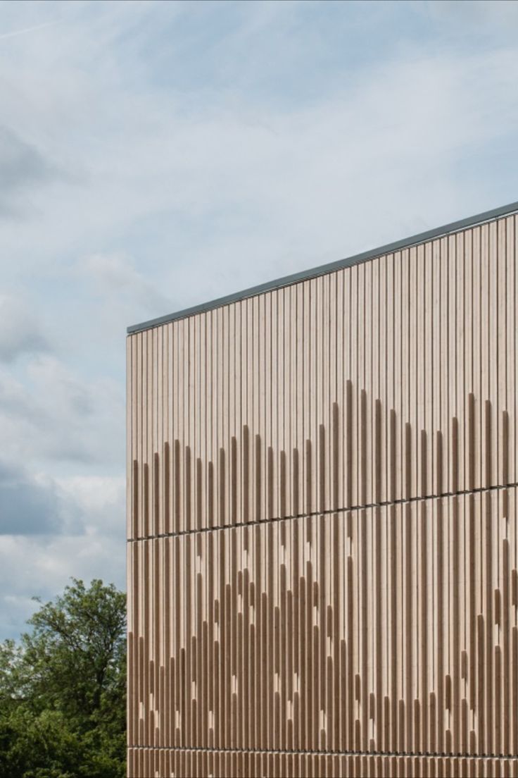 a tall building with wooden slats on the side and trees in front of it