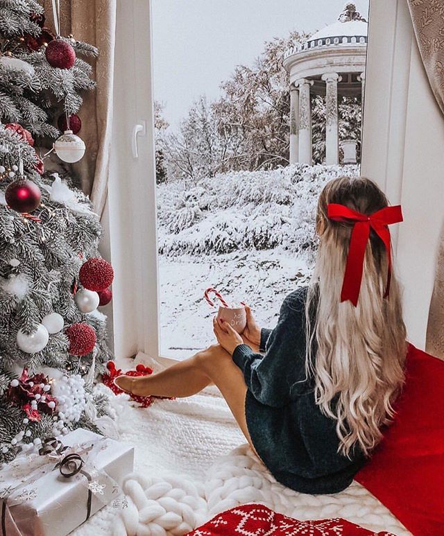 a woman sitting in front of a christmas tree