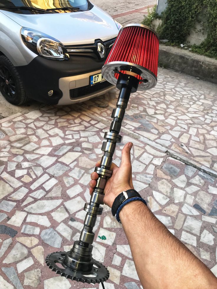 a person holding up a lamp on the street next to a parked car and another vehicle