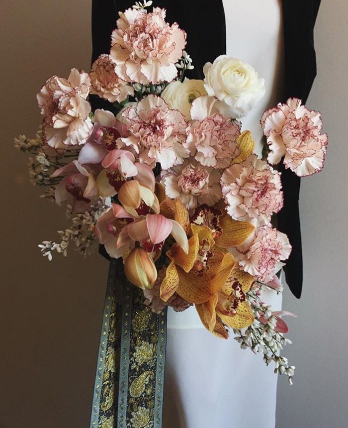 a woman holding a bouquet of flowers in her hand and wearing a black blazer