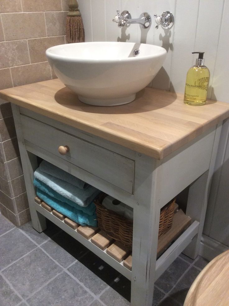 a bathroom sink sitting under a white bowl on top of a wooden counter next to a toilet