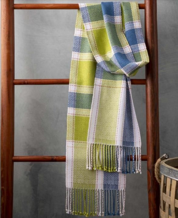 a green and blue checkered scarf hanging on a wooden ladder next to a basket