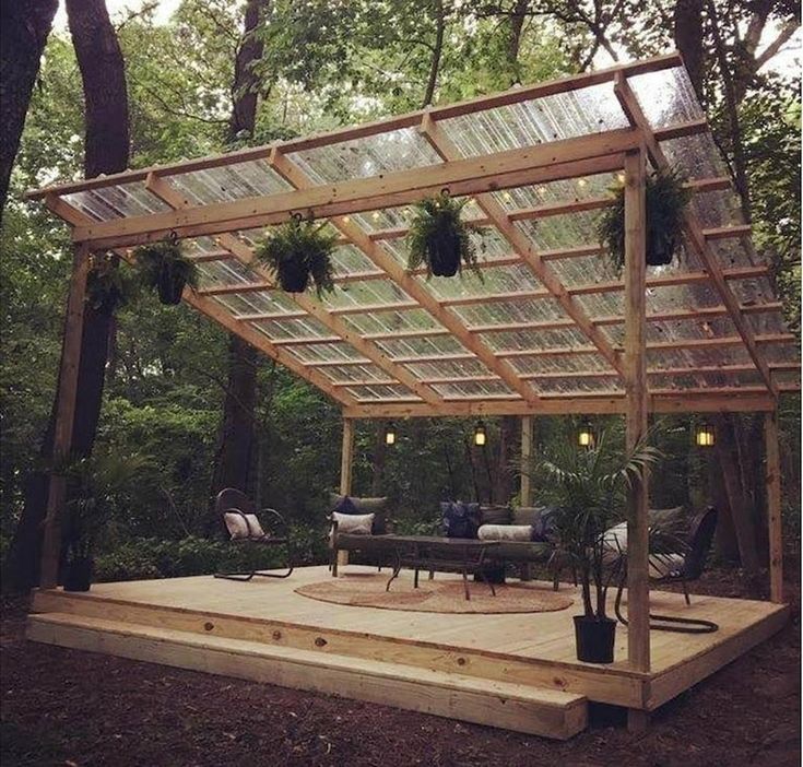 an outdoor patio with a pergolated roof and seating area surrounded by trees in the background