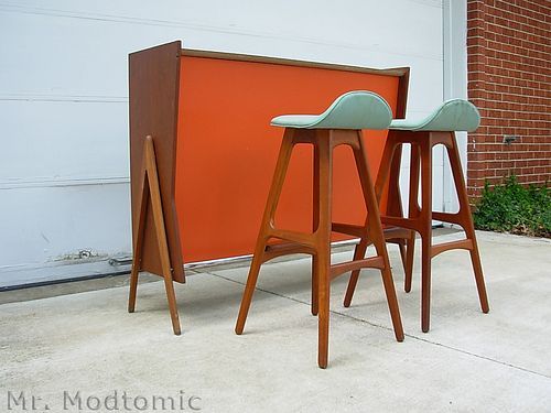 two wooden barstools sitting next to each other in front of an orange wall