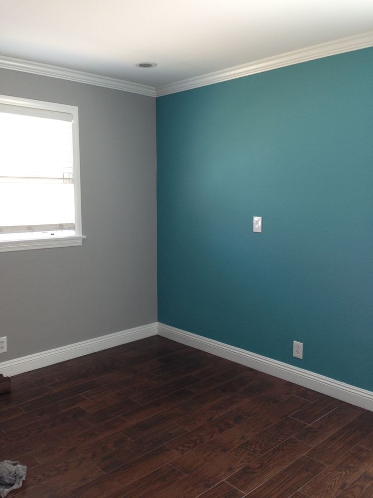 empty room with hard wood flooring and blue painted walls in the corner, looking towards the window