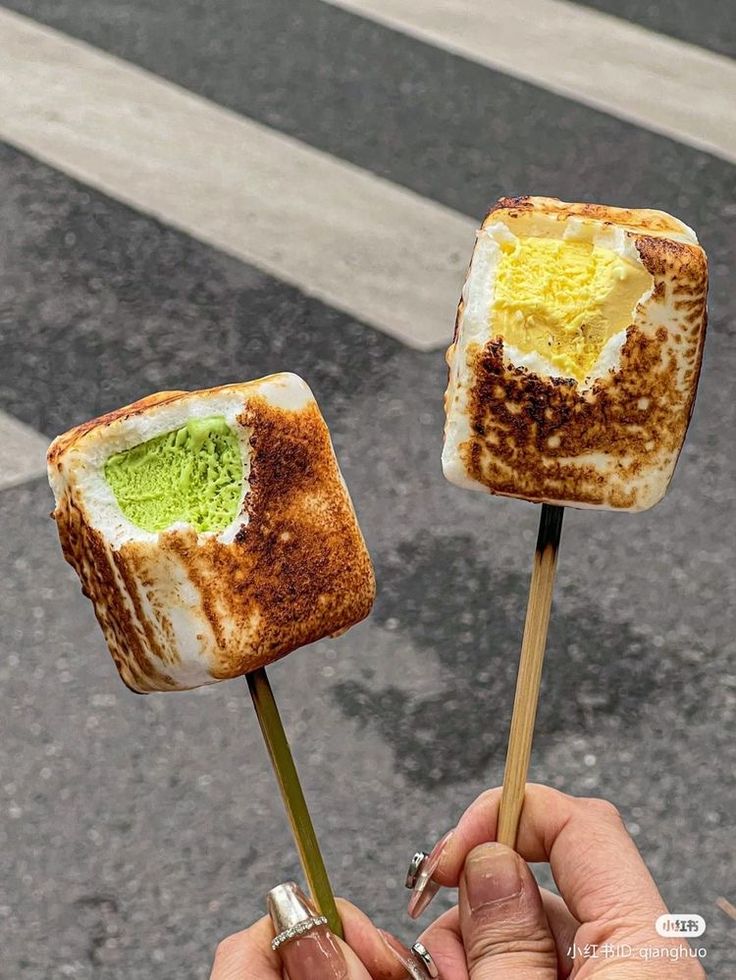 two toasted marshmallows with green and yellow frosting on them in the street