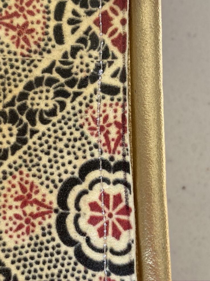 a close up view of the inside of a purse with gold trim and floral designs on it