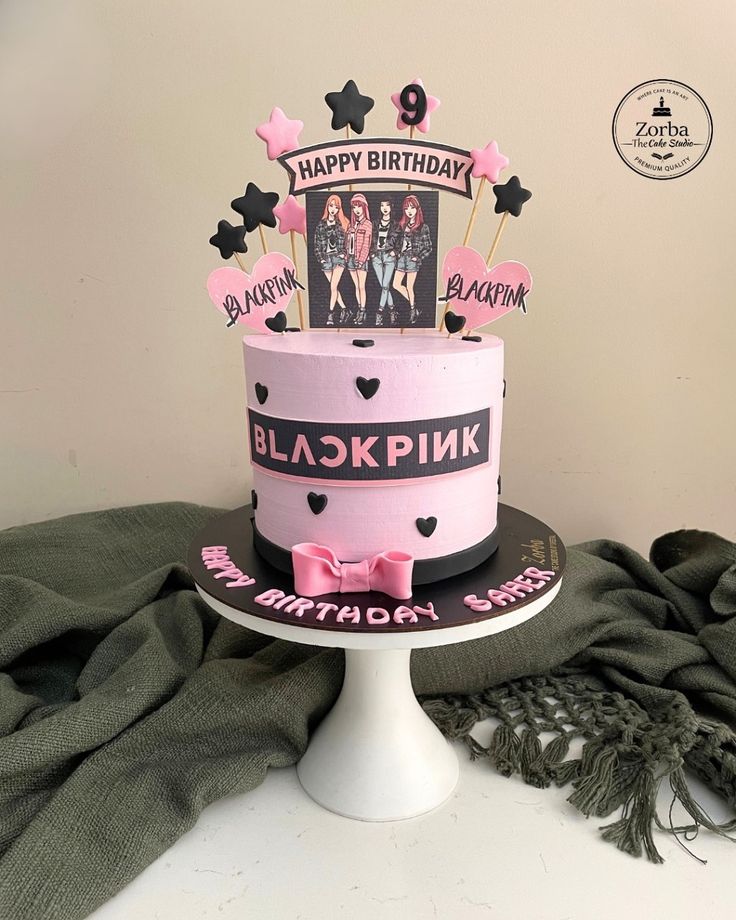 a pink and black birthday cake sitting on top of a table