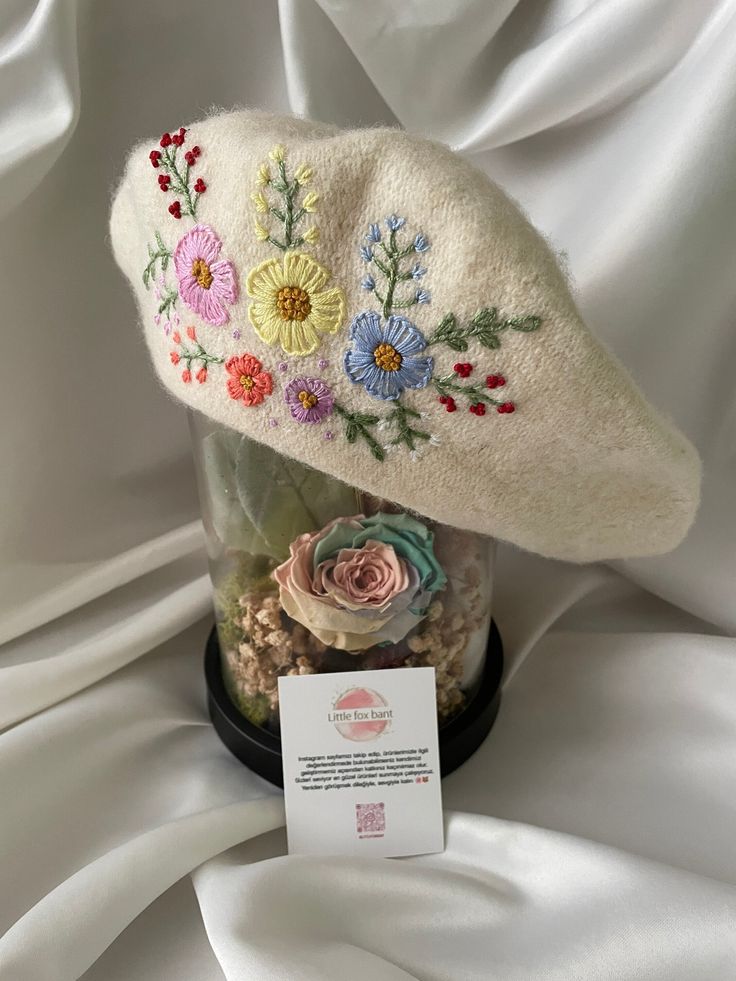 a white hat with flowers on it and a price tag in front of the cap