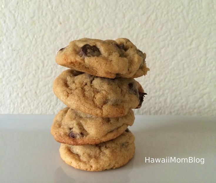 three chocolate chip cookies stacked on top of each other in front of a white wall