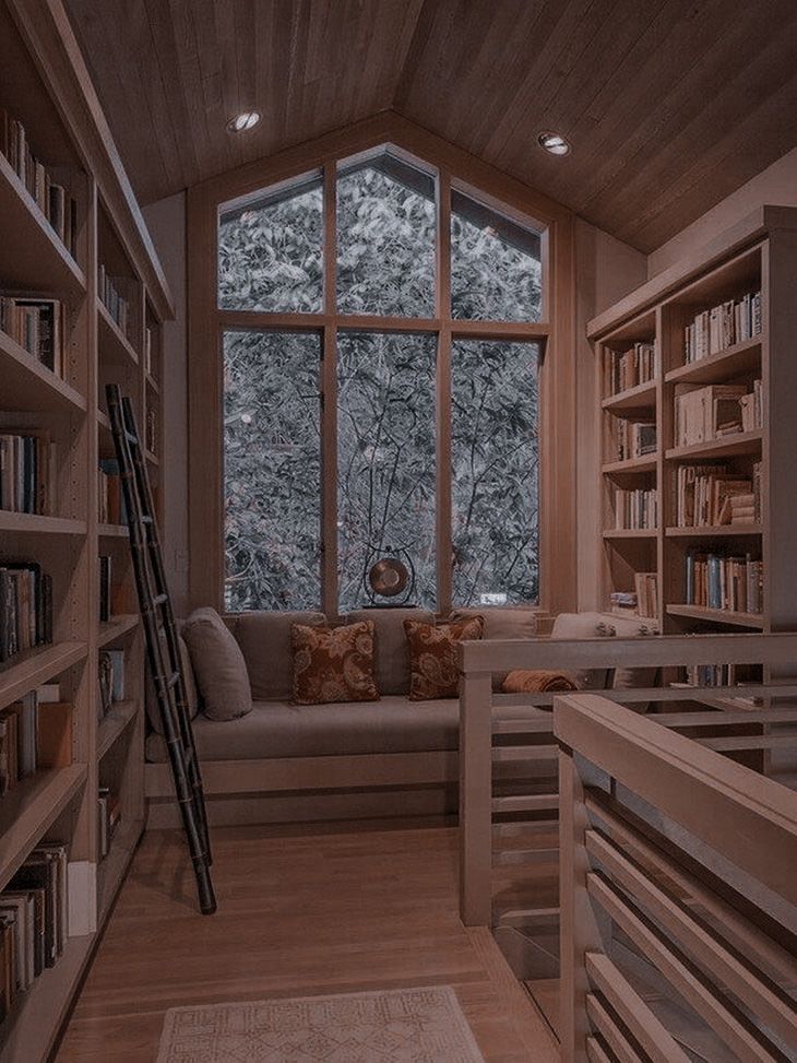 a living room filled with lots of furniture and bookshelves next to a window