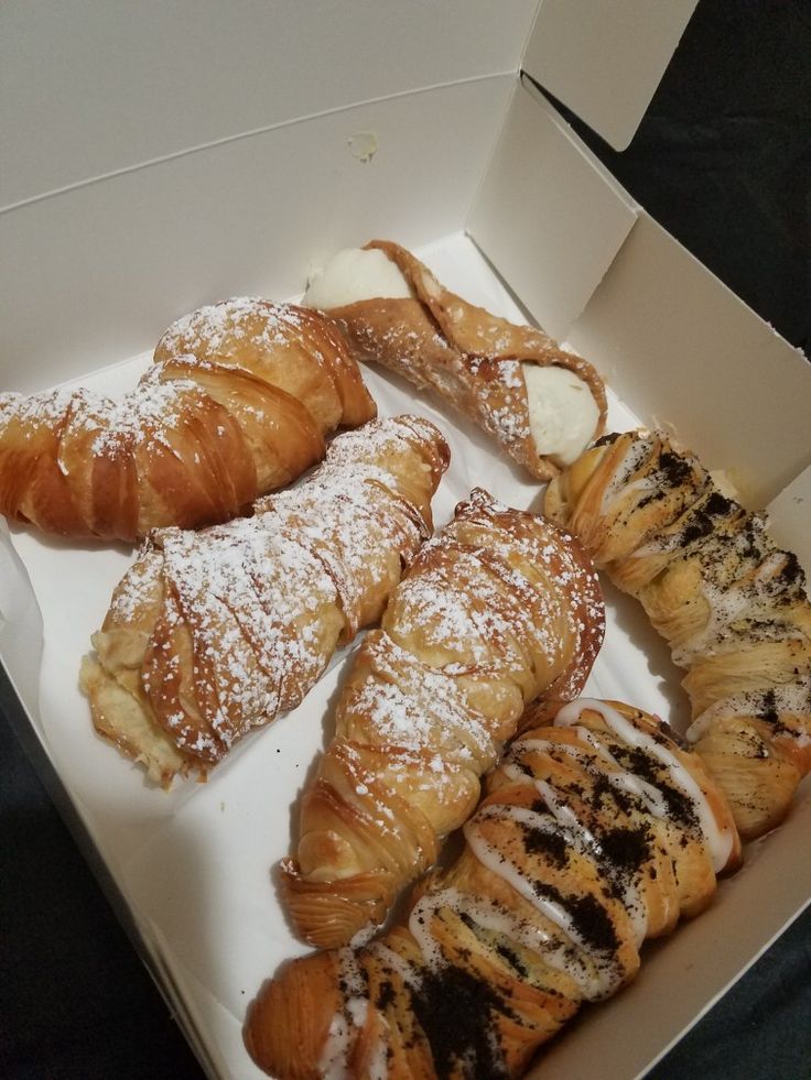 several pastries in a box with powdered sugar on top