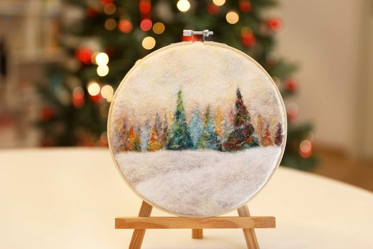 a christmas tree is in the background behind a small round ornament on a wooden stand