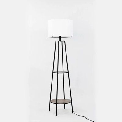 a floor lamp with a white shade on the top and a black stand underneath it