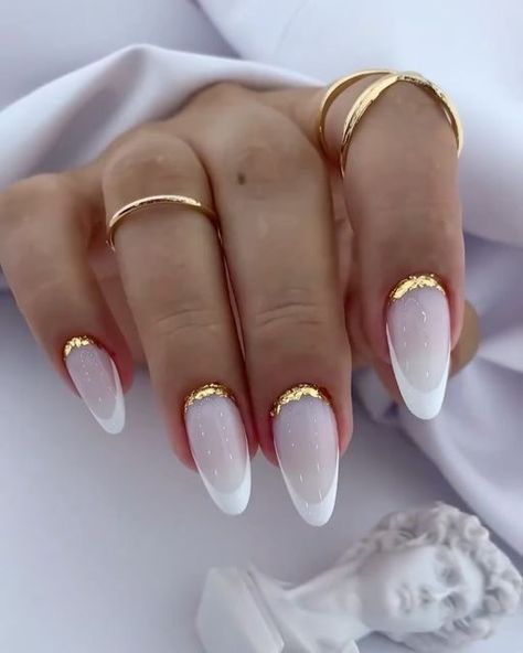 a woman's hand with white and gold nail polish