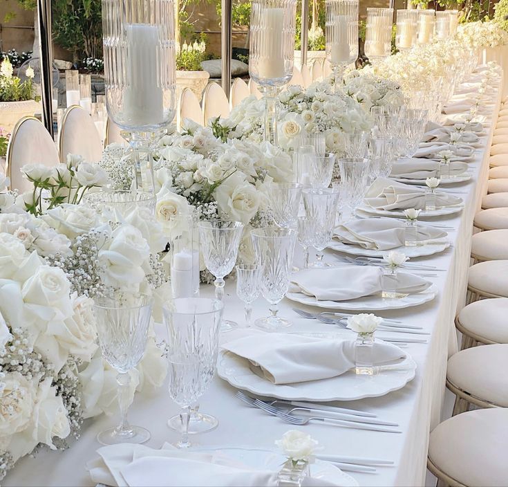 a long table is set with white flowers and place settings