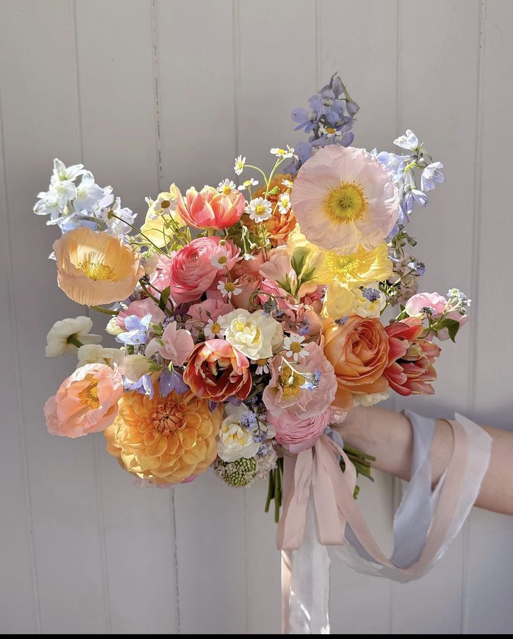 a woman holding a bouquet of flowers in her hand with ribbons around it's neck