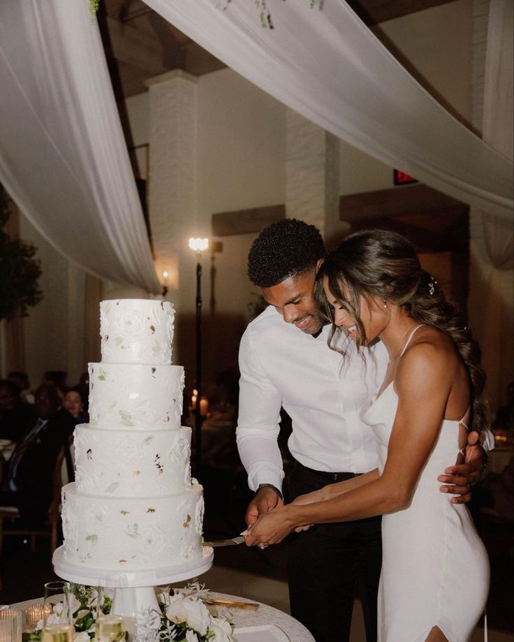 a man and woman cutting into a wedding cake