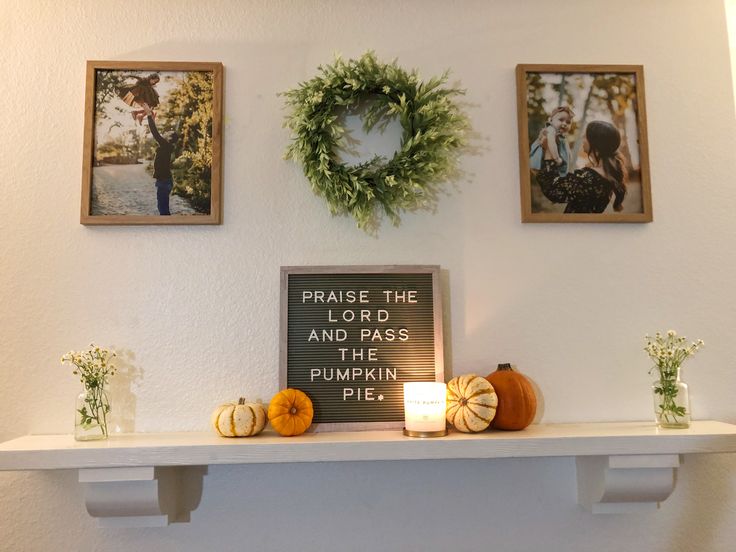 the mantle is decorated with pumpkins and greenery for fall decorations, along with two framed photos