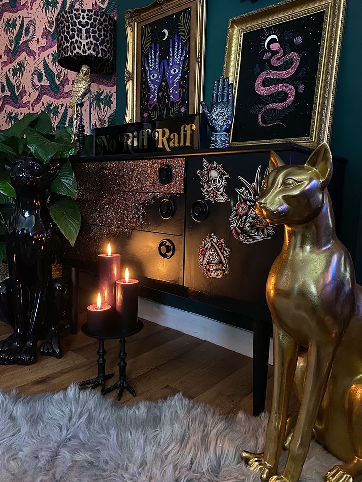 a cat statue sitting on top of a wooden floor next to a table with candles