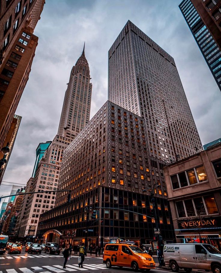 an intersection in new york city with tall buildings and cars driving on the street at dusk