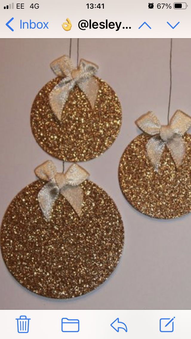 three gold glittered ornaments with bows on them