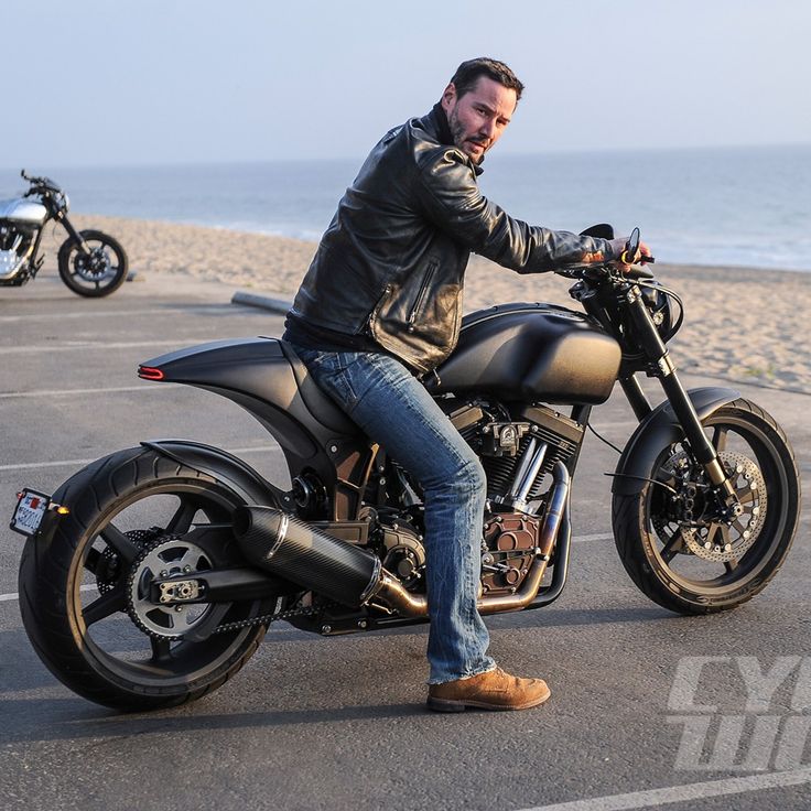 a man sitting on top of a motorcycle in a parking lot next to the ocean