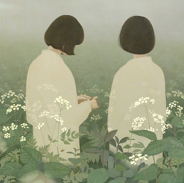 two people standing in the grass with flowers on their backs and one person holding a cell phone