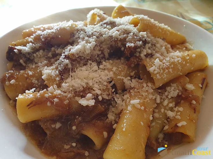 a white plate topped with pasta covered in sauce and parmesan sprinkles