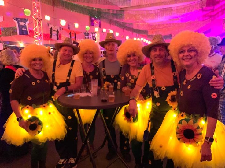 a group of people dressed in costumes and wigs posing for a photo at a party