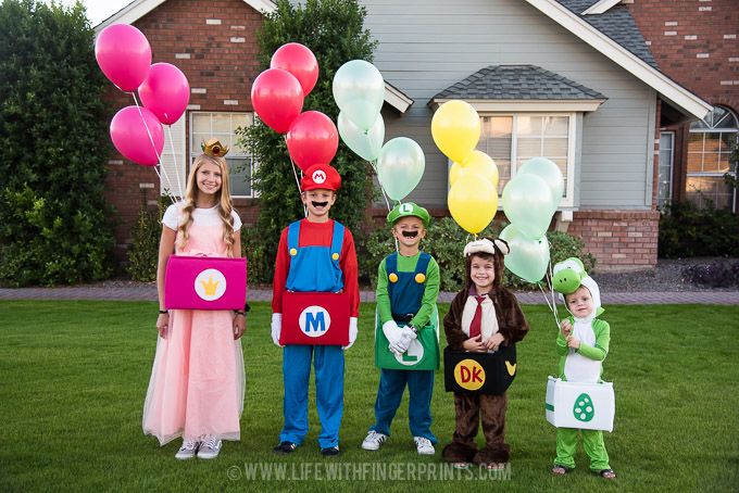 some kids are dressed up as mario and luigi in front of a house with balloons