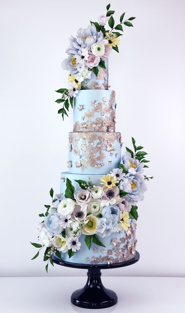 a three tiered blue cake with flowers on it