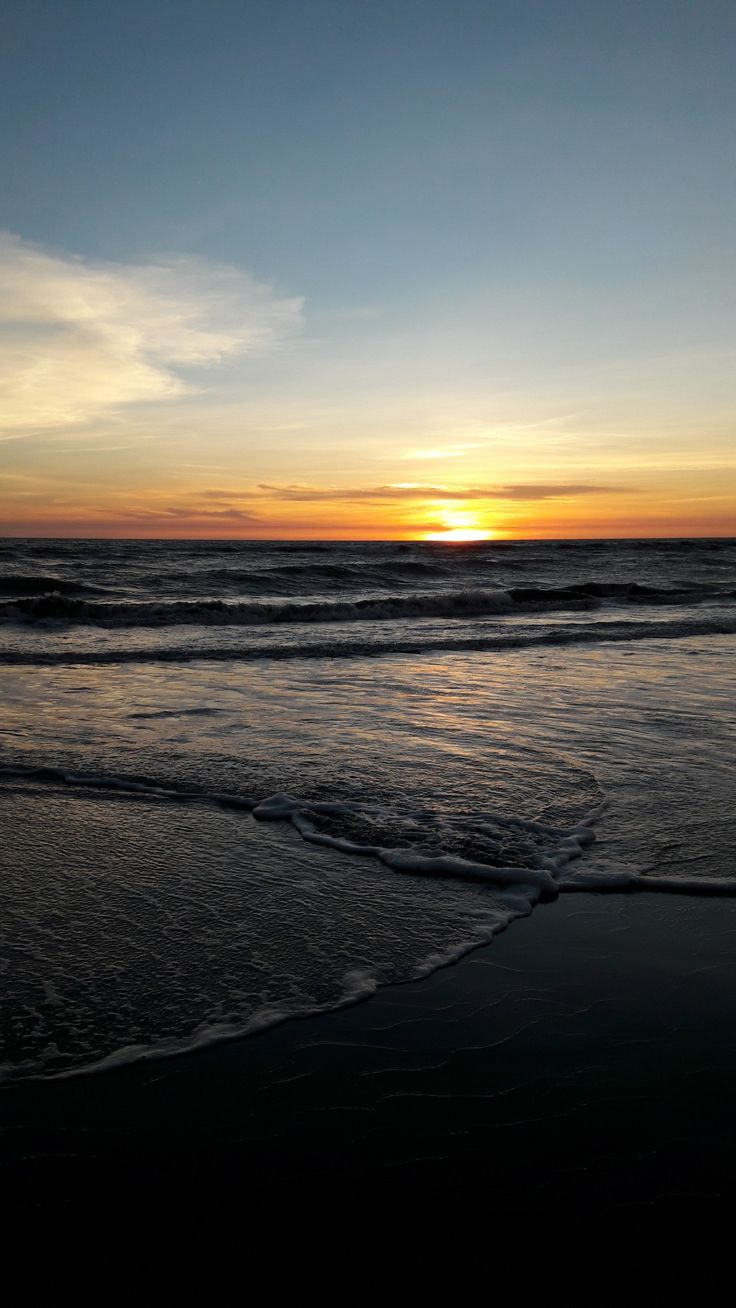 the sun is setting over the ocean with waves