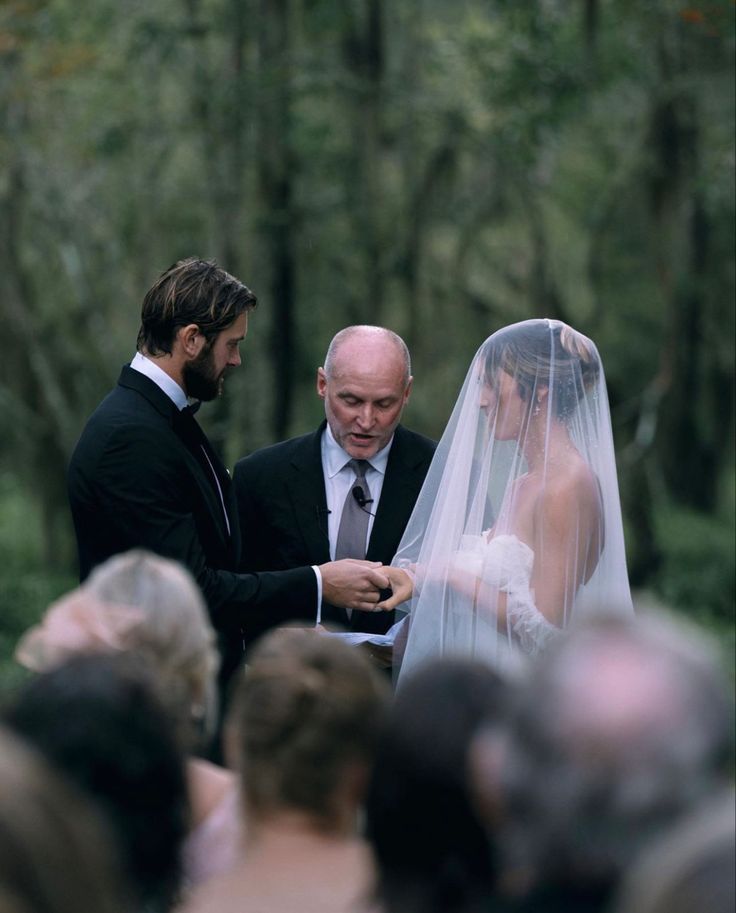 a man in a suit and tie standing next to a woman wearing a wedding veil