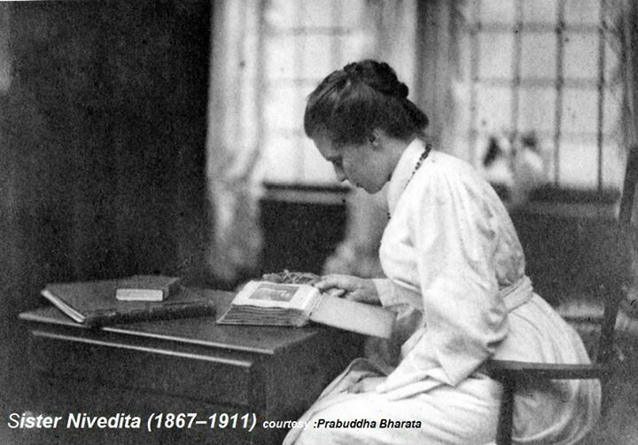 an old black and white photo of a woman sitting at a desk with a book