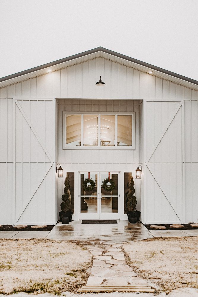 a large white barn with two doors and wreaths on the front door is shown